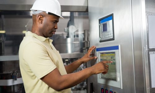 Confident male employee operating machine in manufacturing industry